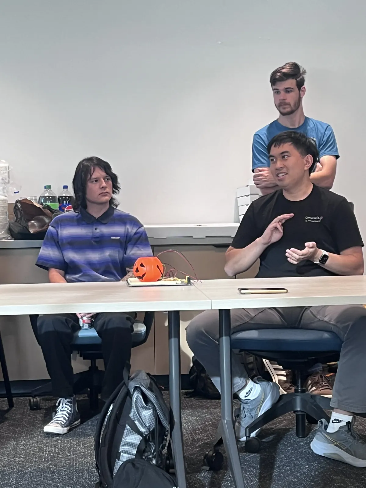 Members chatting at a table with a small jack-o'-lantern in front of them